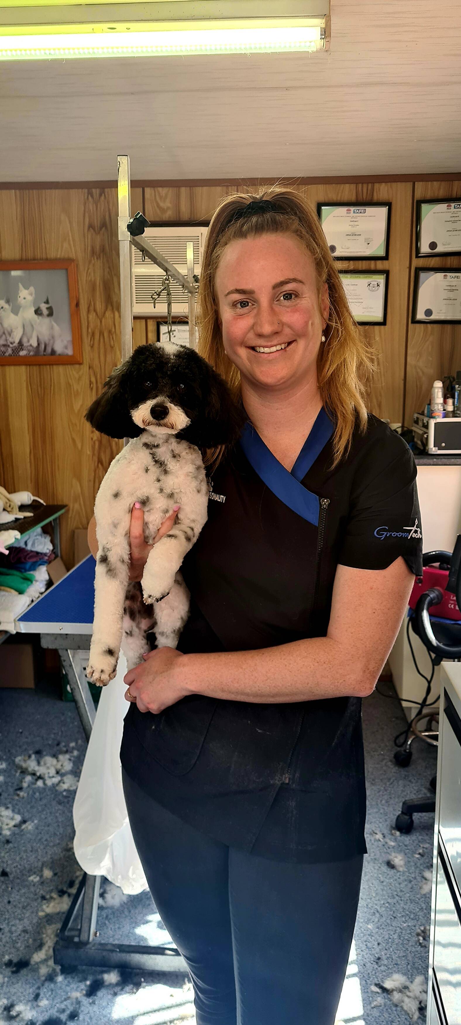 Jorja, the groomer at Pets with Pawsonality, holding a freshly groomed dog